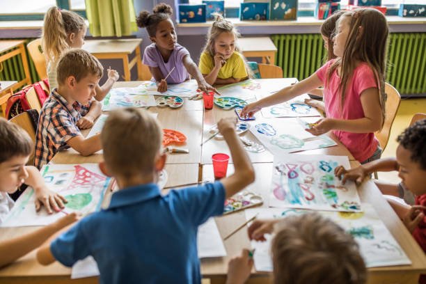 Group of students painting with water colors on art class at elementary school.